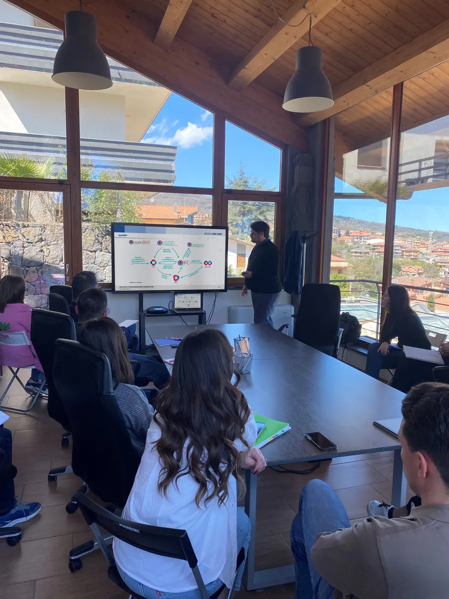 Una lezione del modulo BIM Start in sala riunioni: il docente spiega il flusso openBIM al team seduto attorno al tavolo